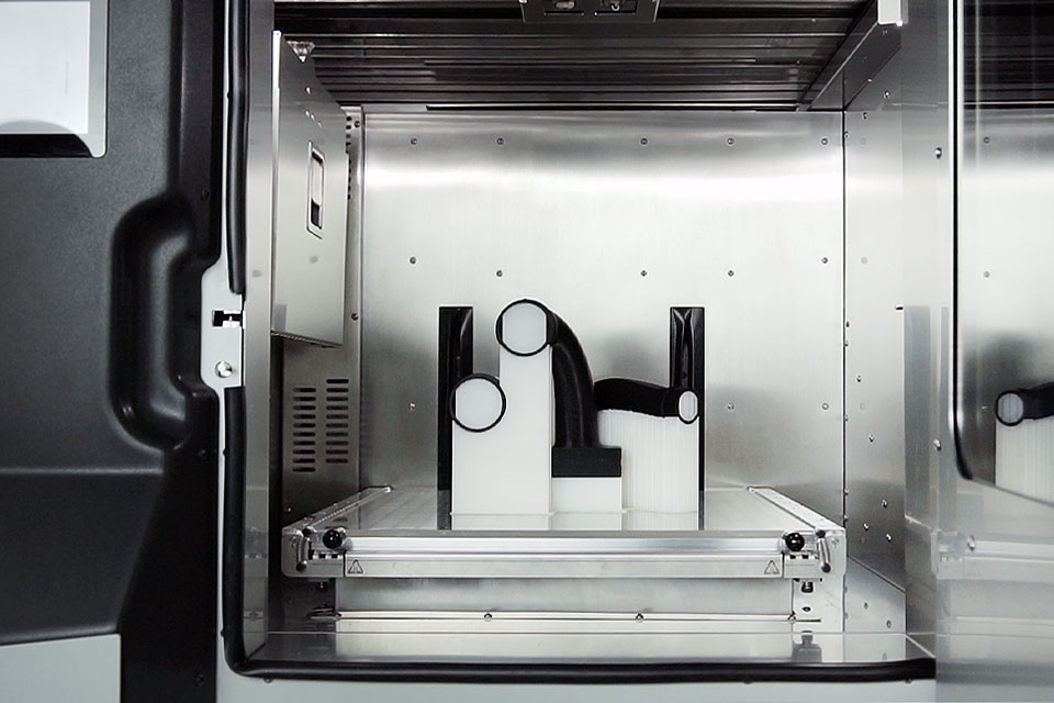 ndustrial 3D printer INDUSTRY F340. Close-up of name. View of printing chamber with printout inside.